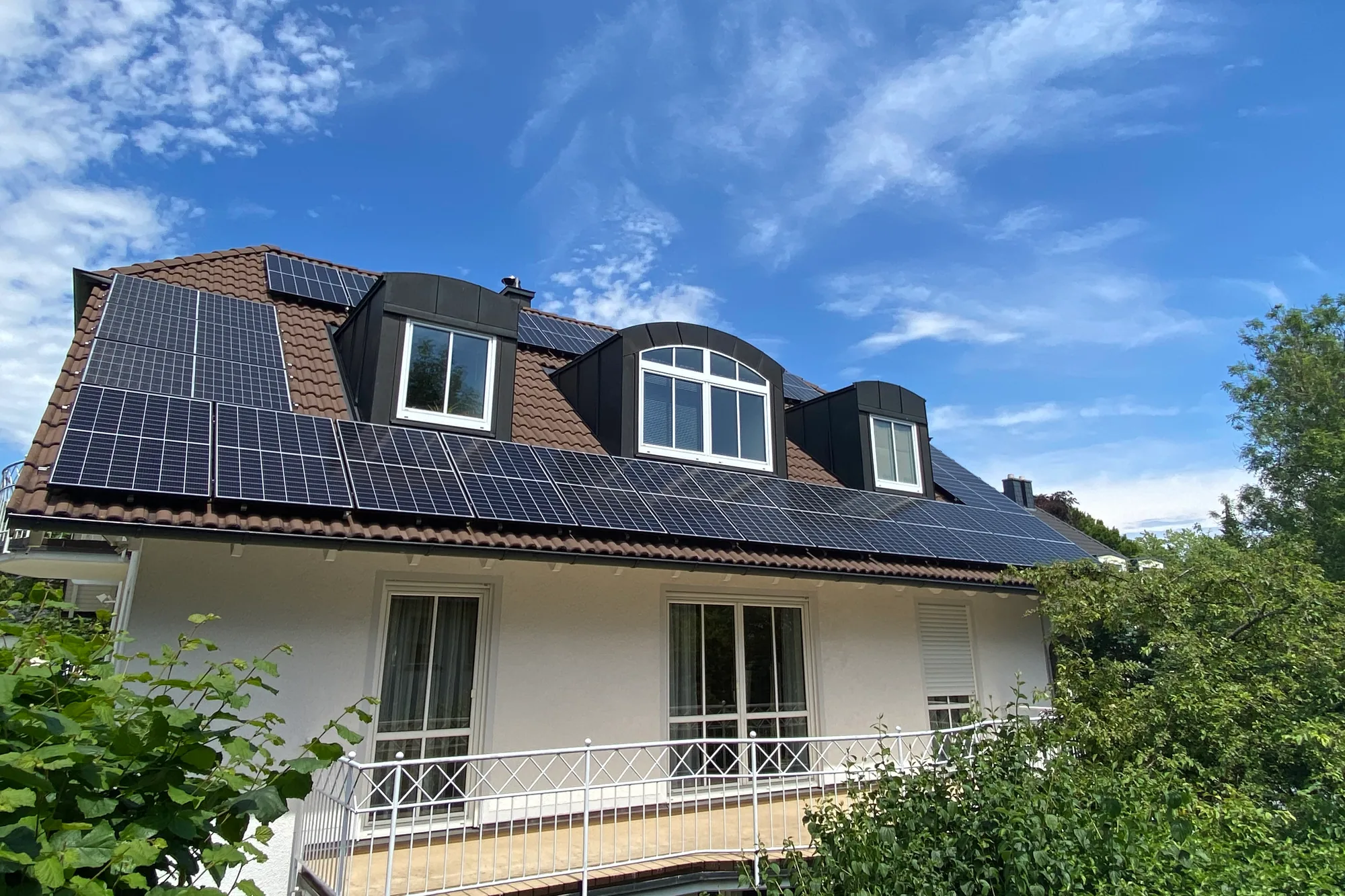 Einfamilienhaus mit drei Gauben und Photovoltaik-Modulen auf dem Satteldach