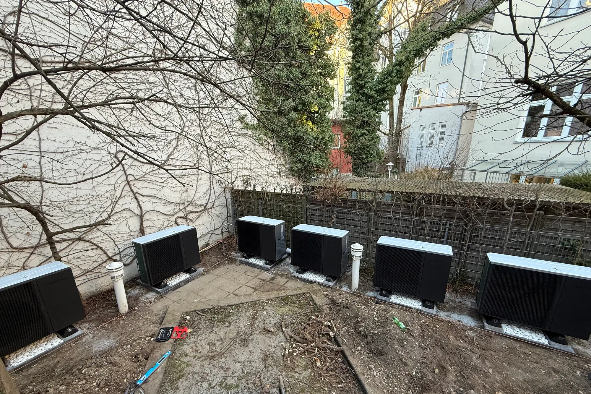 Sechs Wärmepumpen-Außeneinheiten in einer Reihe im Innenhof
