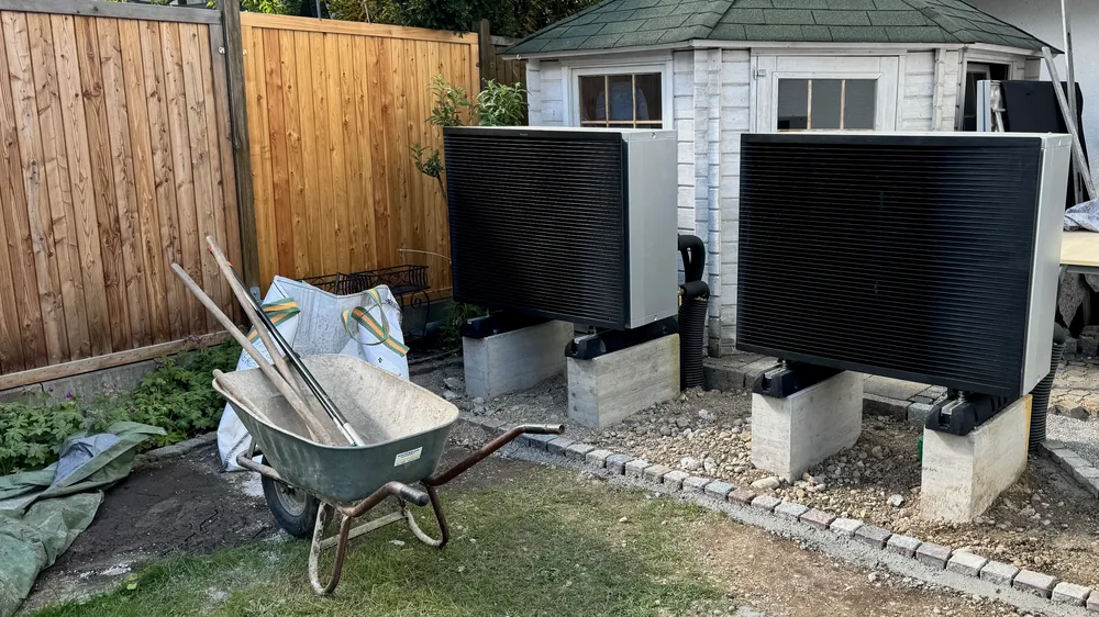 Zwei Wärmepumpen-Außeneinheiten auf Betonsockeln im Garten, während der Montage