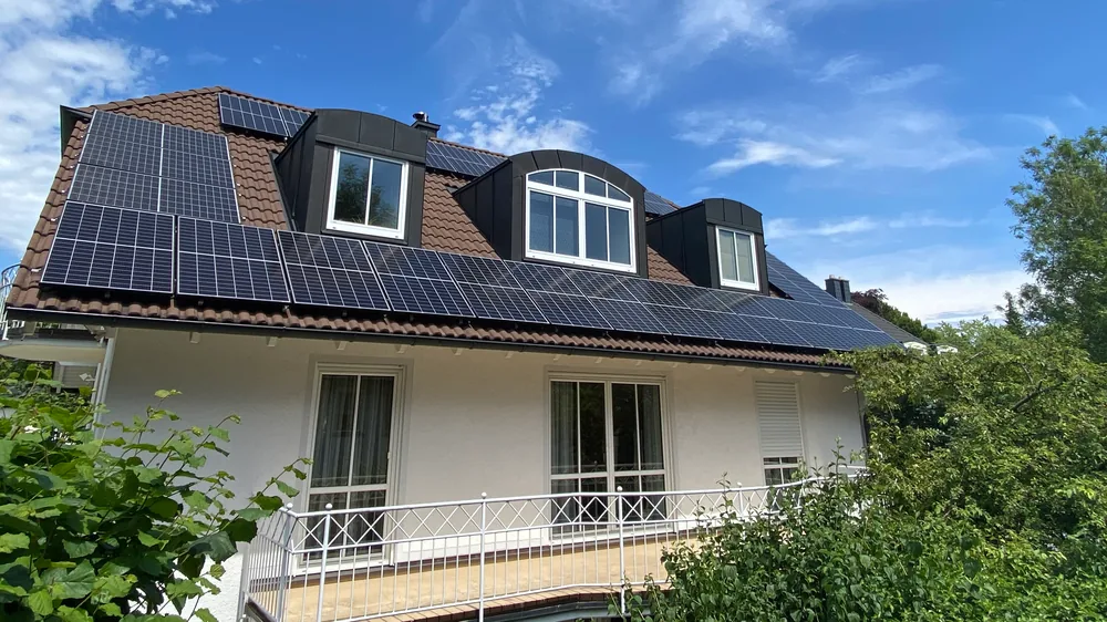 Einfamilienhaus mit drei Gauben und Photovoltaik-Modulen auf dem Satteldach