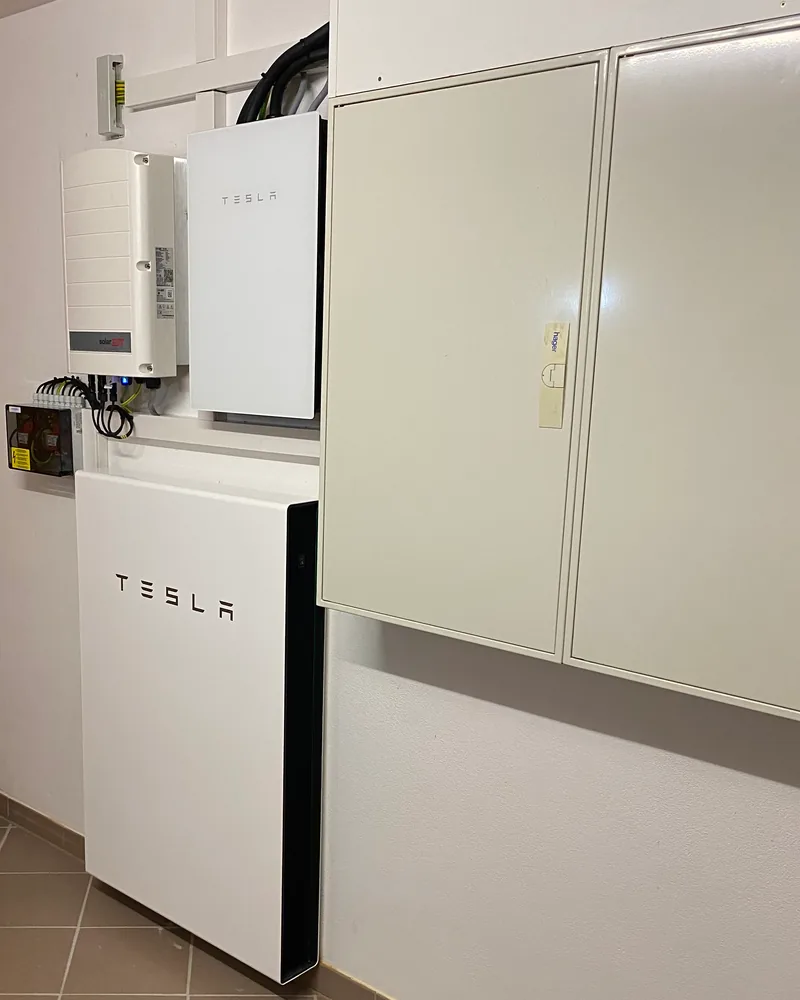 Tesla-Batteriespeicher und Wechselrichter an der Wand im Technikraum